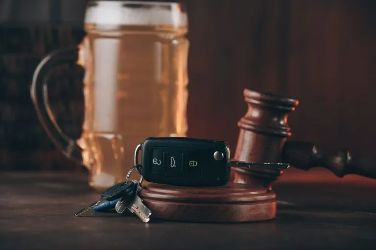 a car key alongside a gavel and a cup of bear on a table