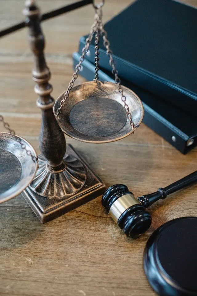 Bronze scales of justice and judge's gavel on wooden desk