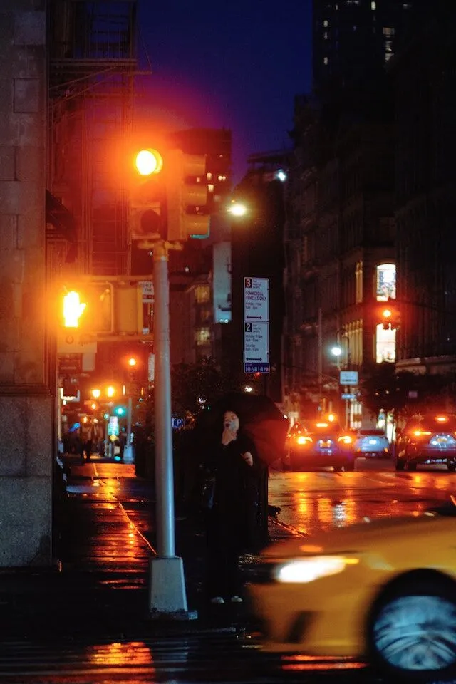 City intersection at night with glowing traffic lights and wet streets