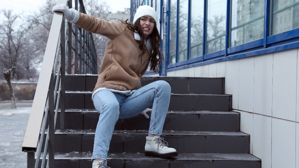 Young woman fallen on slippery stairs covered with ice outdoors_s Young woman fallen on slippery stairs covered with ice outdoors