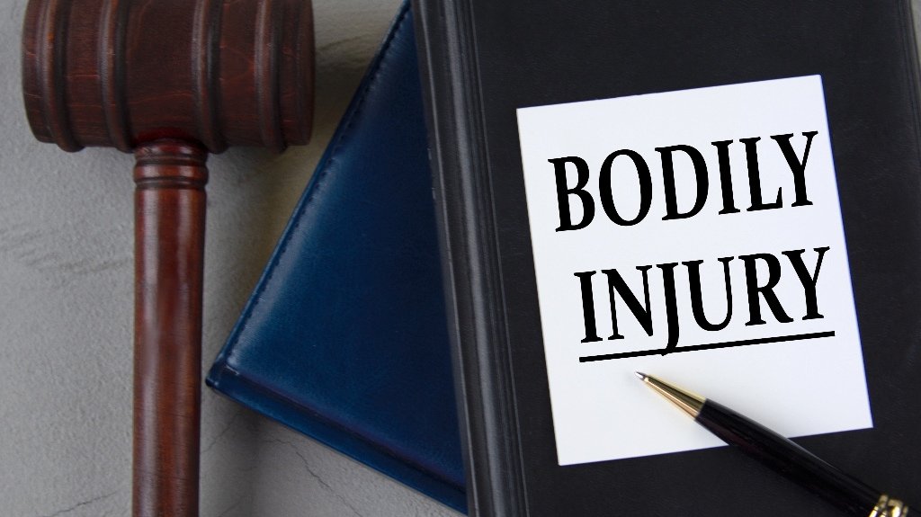 BODILY INJURY – words on a white sheet with leather notebooks_s Bodily Injury Legal Term On Law Book And Gavel