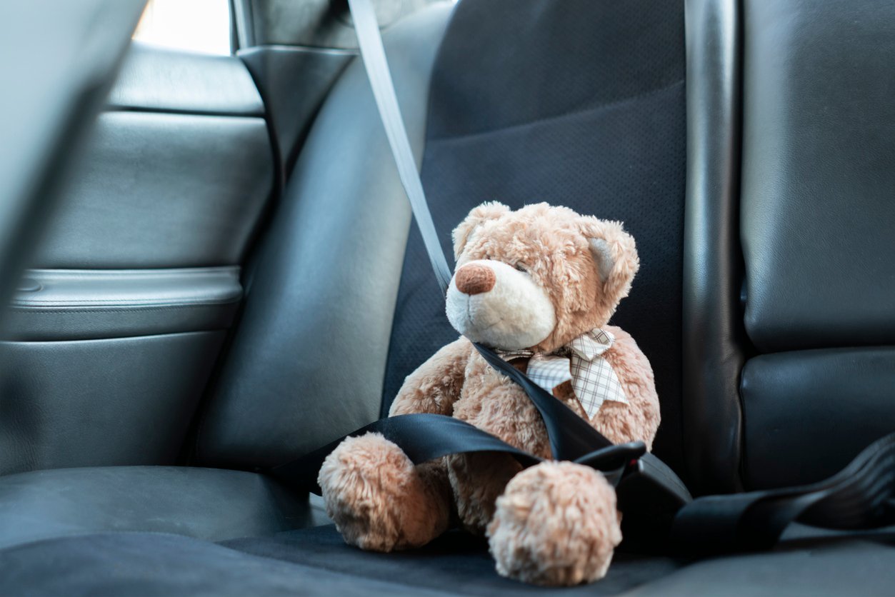 Child’s teddy bear buckled with seatbelt showing child car safety after accident